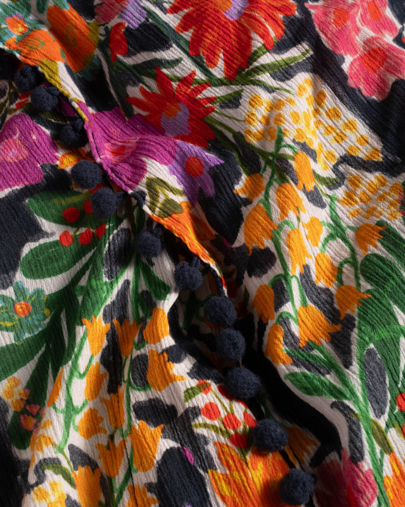 Close-up of a colorful fabric with floral embroidery and tassels.