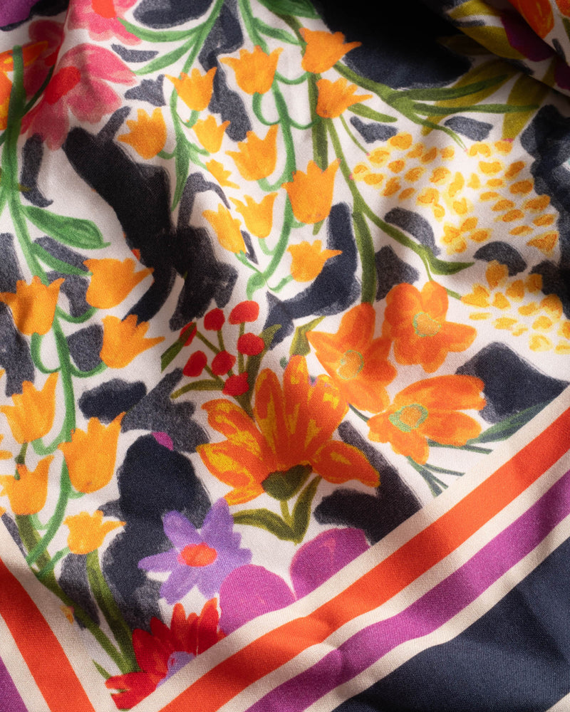 Colorful floral patterned fabric with orange, purple, and black flowers.