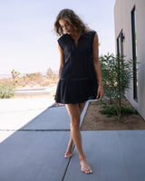 Woman in a black dress standing on a patio with a desert landscape in the background
