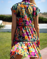 Woman wearing a colorful floral dress with a clear blue sky and green grass background