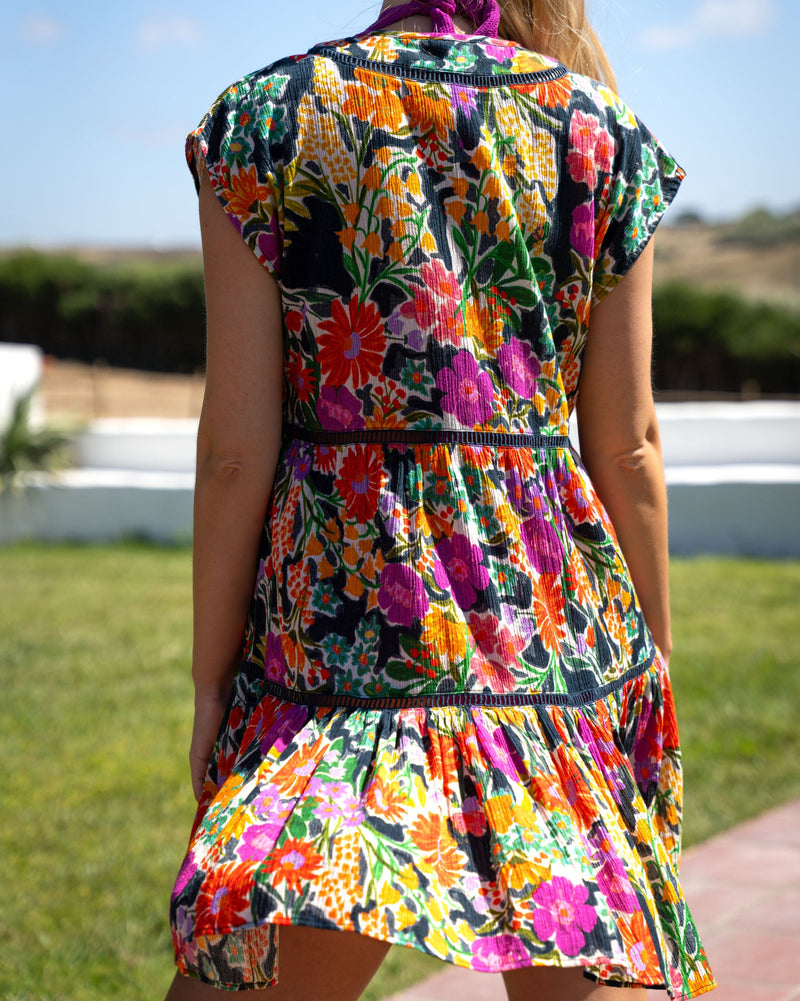 Woman wearing a colorful floral dress with a clear blue sky and green grass background