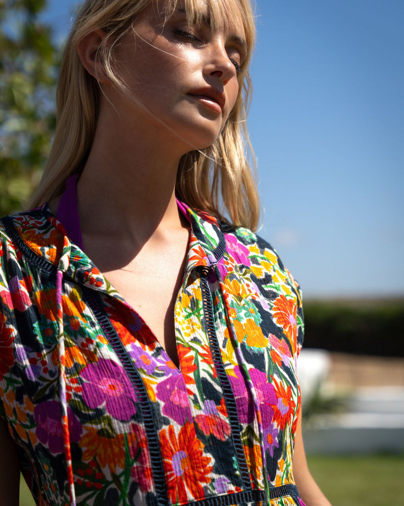 Woman wearing a colorful floral dress against a blue sky.