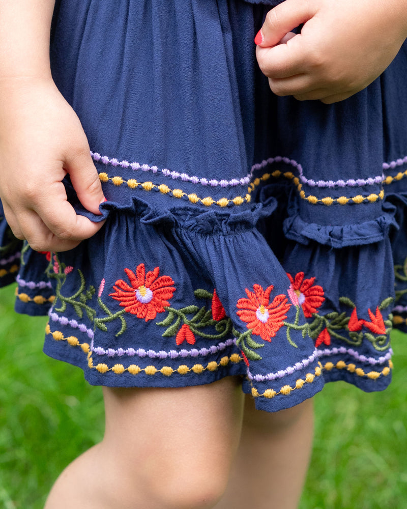 Navy blue dress with floral embroidery on a blurred green background