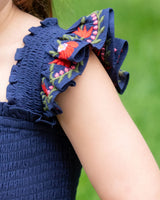 Navy blue dress with floral embroidery on a blurred green background