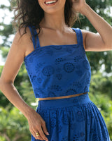 Woman wearing a blue dress with floral patterns against a blurred green background