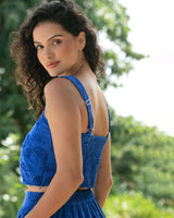 Woman in a blue dress standing outdoors with greenery in the background