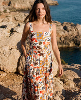 Woman in a colorful dress standing on rocky terrain near water