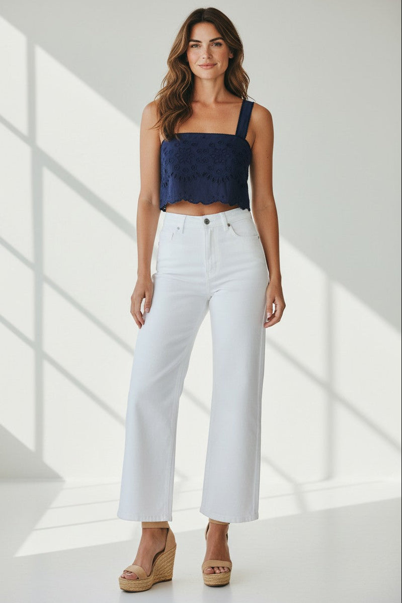 Woman wearing a navy top and white pants in a bright room