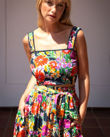 Woman wearing a colorful floral dress against a plain background