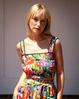 Woman wearing a colorful floral dress against a plain background