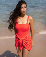 Woman in a red dress standing on a beach with ocean in the background