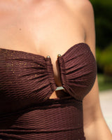 Close-up of a strapless brown dress with gold buttons on a blurred background