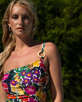 Woman wearing a colorful floral swimsuit with a blurred green background