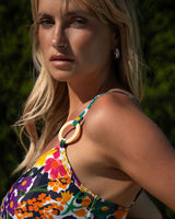 Woman wearing a colorful floral swimsuit with a blurred green background