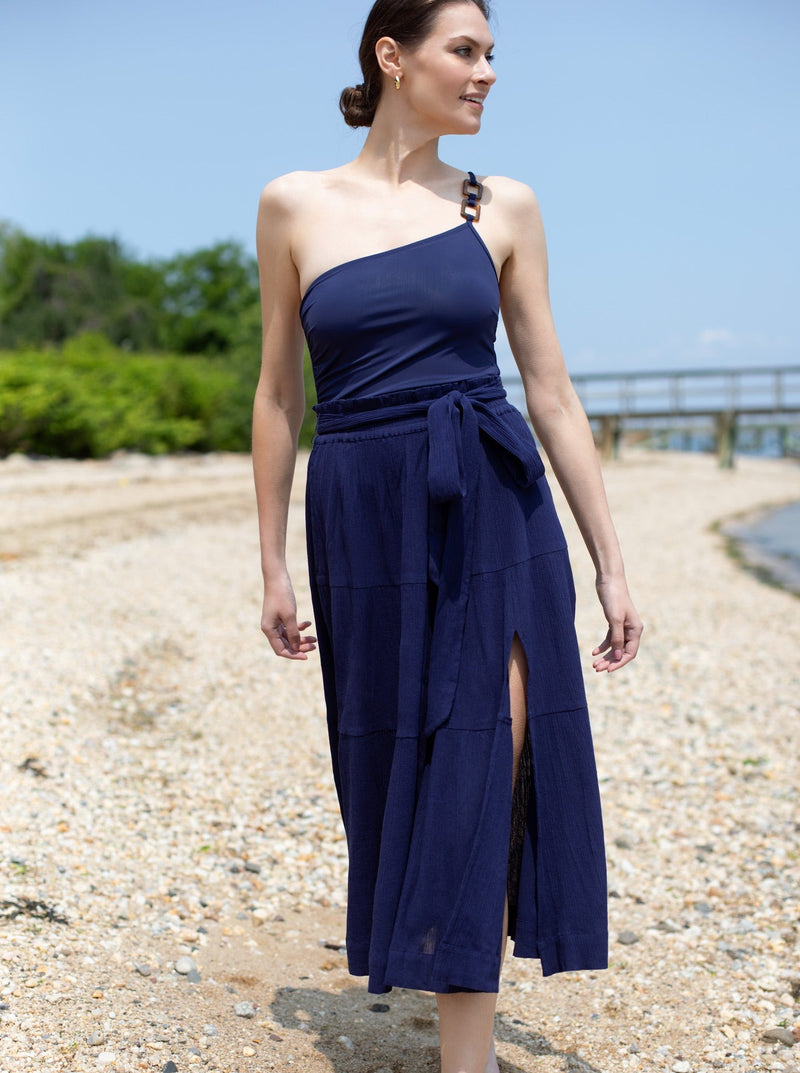Model looking towards ocean in long navy skirt