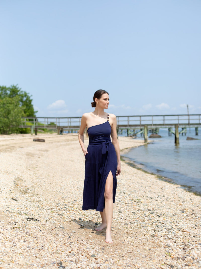 Model standing and looking at water in long navy skirt