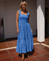 Woman wearing a blue dress standing on a tiled floor.