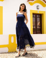 Woman in a navy blue dress standing in front of a white wall with yellow accents.