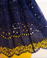 Navy blue skirt with intricate yellow and white lace details on a white background