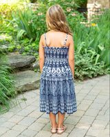 Woman wearing a blue patterned dress standing in a garden.