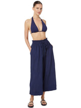 Model wearing navy blue organic cotton beach pants with elastic waistband with drawstring and tassel detail with matching navy blue triangle bikini top