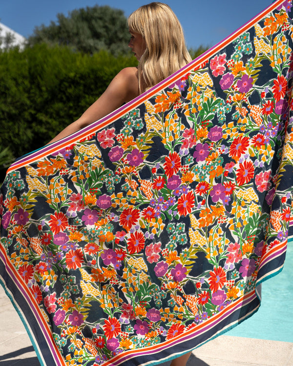 Woman holding a colorful floral towel by a poolside