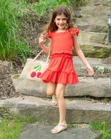 Young girl in a red dress standing on stone steps with a garden background