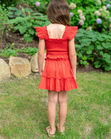 Young girl in a red dress standing in a garden