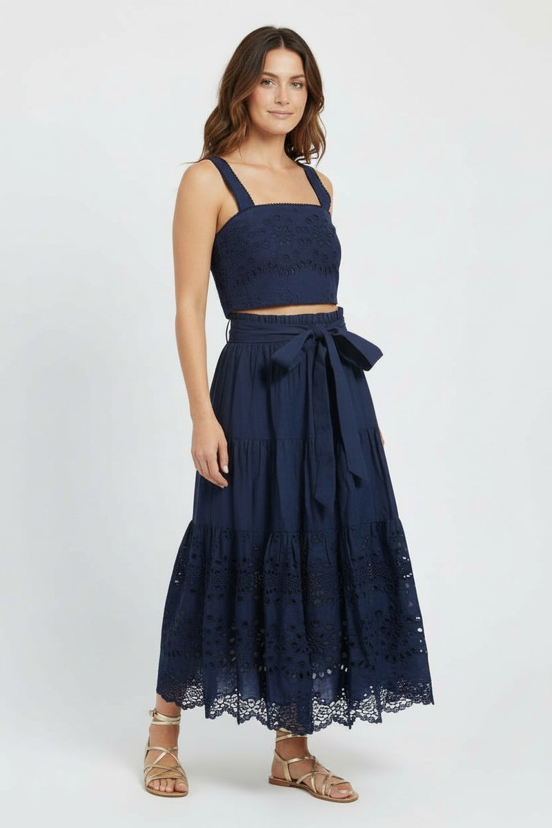Woman wearing a navy blue lace top and skirt set on a white background