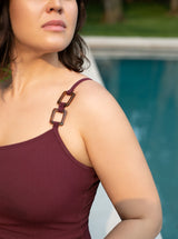 Close up of shoulder strap on model of burgundy one strap one piece bathing suit