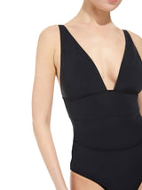 close up shot of a model wearing french cup black one piece swimsuit with a deep plunge-neckline, adjustable back straps, and shirring at the front waist with power compression mesh lining at the front lower torso