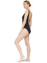the side of model wearing a black classic tank silhouette one piece swimsuit with lace-up front and deep open back