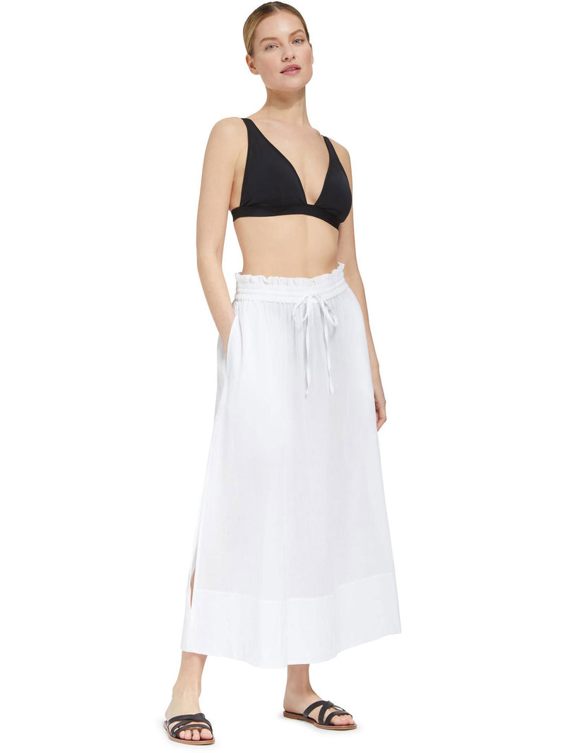Model wearing fresh white midi length skirt with side slits and elastic waistband with drawstring detail with black v-neck bikini top and black sandals