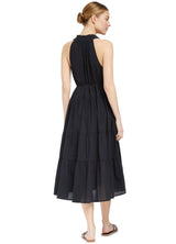 The back of a model wearing a black sleeveless, high neck with ruffle detail, buttoned shirt dress with optional matching belt with tassels