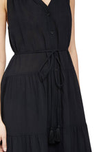 Close up and detailed shot of model wearing a black colored sleeveless, high neck with ruffle detail, buttoned shirt dress with optional matching belt with tassels