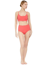 Model wearing a coral scoop neckline bikini top with under-bust band and adjustable straps with matching high rise bikini bottom 