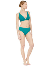 Model looking to the side and wearing a green plunge neckline, classic bikini topwith adjustable straps and an elastic underband with a matching classic midrise bikini bottom