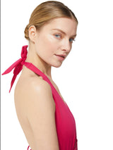 profile view of model wearing fuchsia deep plunged one piece swimsuit with an adjustable halter-neck tie and under-bust string 