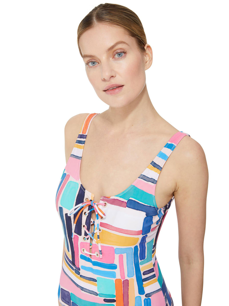 close up shot of a model wearing a geometric and graphic colored classic tank silhouette one piece swimsuit with lace-up front 