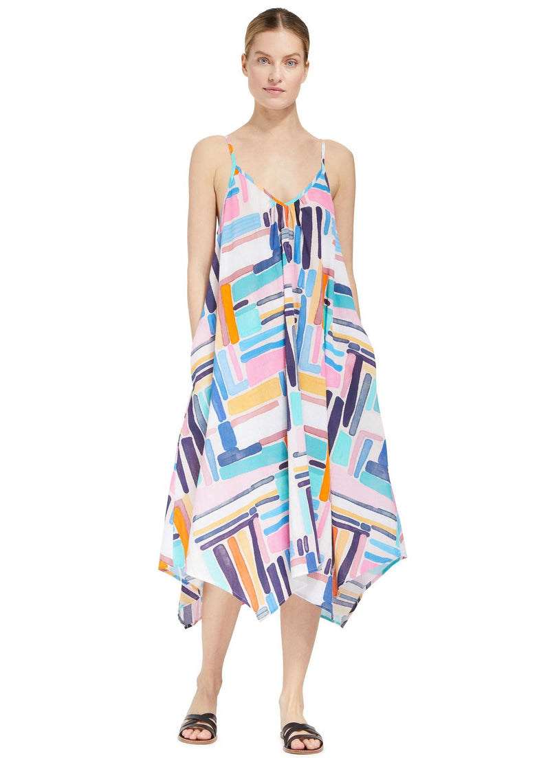 Model posing with hands in her pockets wearing a geometric and graphic colored strappy and long flowy dress with adjustable back shoulder straps, v-neckline front pockets with black sandals