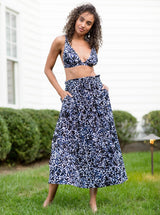 Model in backyard wearing a black and white leopard print midi length skirt with side slits and elastic waistband with drawstring detail with matching v-neck bikini top 