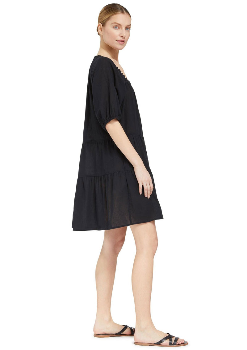 the side of a model wearing a black slightly above the knee dress with rounded neckline and short puff sleeve with a covered elastic cuff 