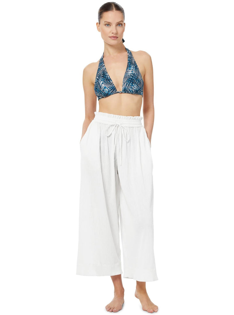 Model wears bikini halter top with teal and white abstract wave print and white cotton straight leg pant with and elastic waistband and string ties in a bow.  