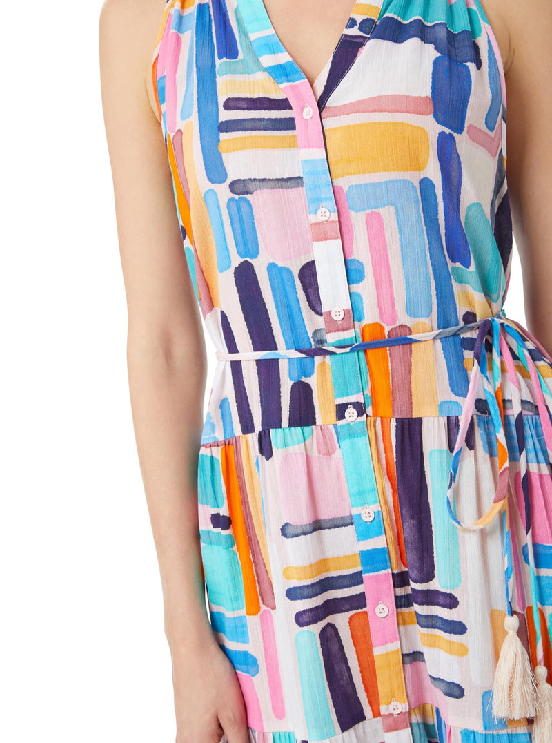 Close up and detailed shot of model wearing a geometric and graphic colored sleeveless, high neck with ruffle detail, buttoned shirt dress with optional matching belt with tassels 