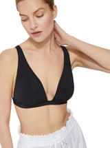 Close up shot of model wearing a black plunge neckline, classic bikini top with adjustable straps and an elastic underband with a white skirt